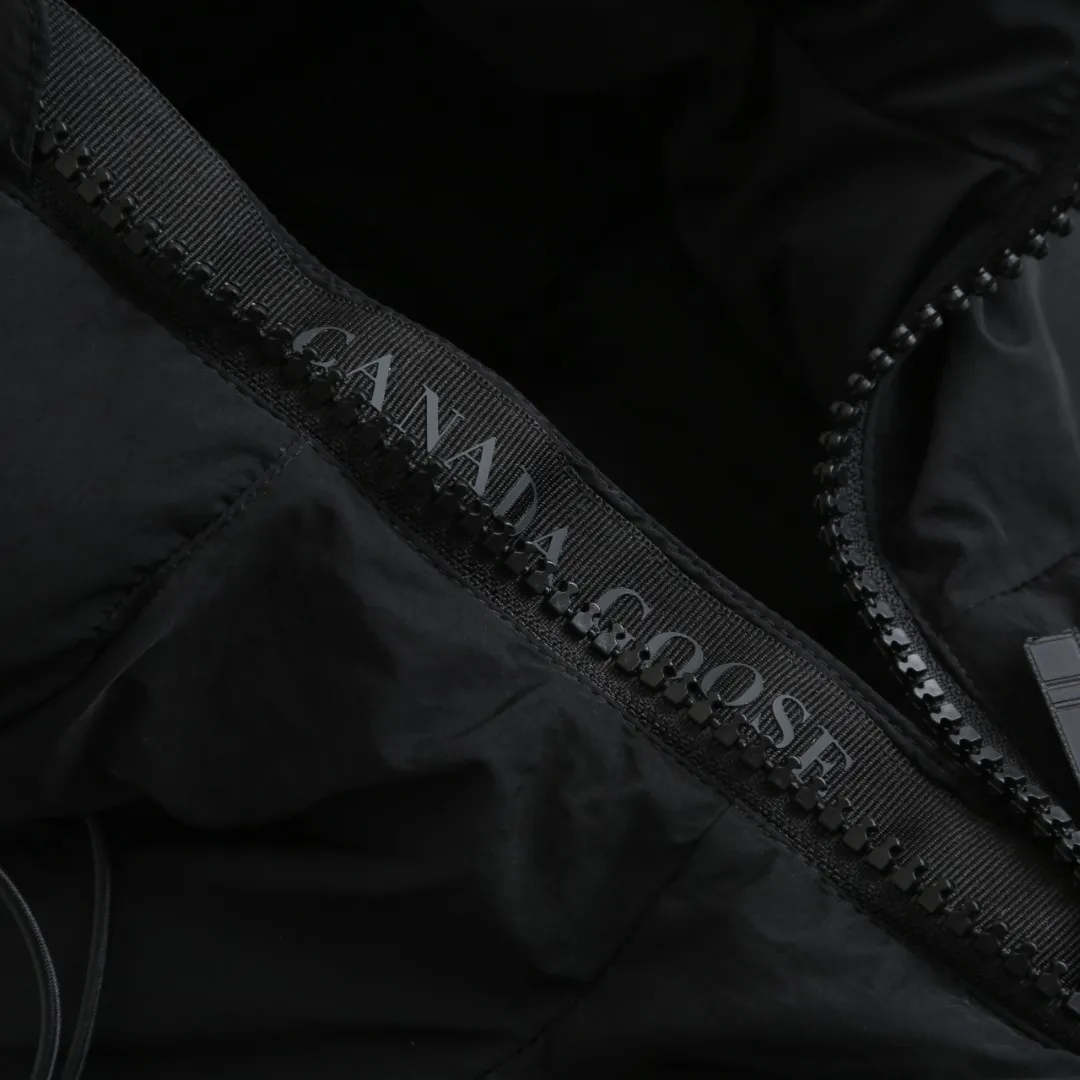 P980 Canada Goose hooded down jacket Fabric selection: Weaved with 400T high-count yarn. After special water-repellent treatment, the surface forms a lotus leaf effect - raindrops will slide down in beads, and snow particles will fall off when touched. The tear resistance reaches 200N (approximately 20kg load-bearing), the light gray matte texture breaks the stereotype of "outdoor clothing = hardcore", and the soft luster presents a high-end matte effect under urban neon lights, seamlessly switching scenes from ski resorts to CBD office buildings.  Process 1: Use polyester woven ribbons as the base, and use high-precision computer embroidery to decorate the brand letters on the ribbons. The edges of the pattern are clear, the stitches are fine and even, and multiple layers of embroidery threads are stacked to enhance the three-dimensional effect.  Process 2: Precision thread reinforcement to prevent velvet drilling and ensure that the fluffy and resilient elasticity lasts as new.  Details: The embedded cuffs are three-dimensionally woven to form a "wavy" elastic structure, forming natural folds when fitting the wrist, increasing the contact area with the skin, thus improving the windproof effect. At the same time, micro-velvet treatment is added to the inside of the cuffs, which feels like a second layer of skin and avoids friction on the skin from metal zippers or hard fabrics.  90 national standard high-quality white duck down: selected high-loft down, weighing 240g, light and warm, with excellent temperature locking performance and good resilience.  Accessories: 1:1 customized armband, 1:1 customized zipper pendant, 1:1 customized elastic buckle, etc. SIZE: S M L XL